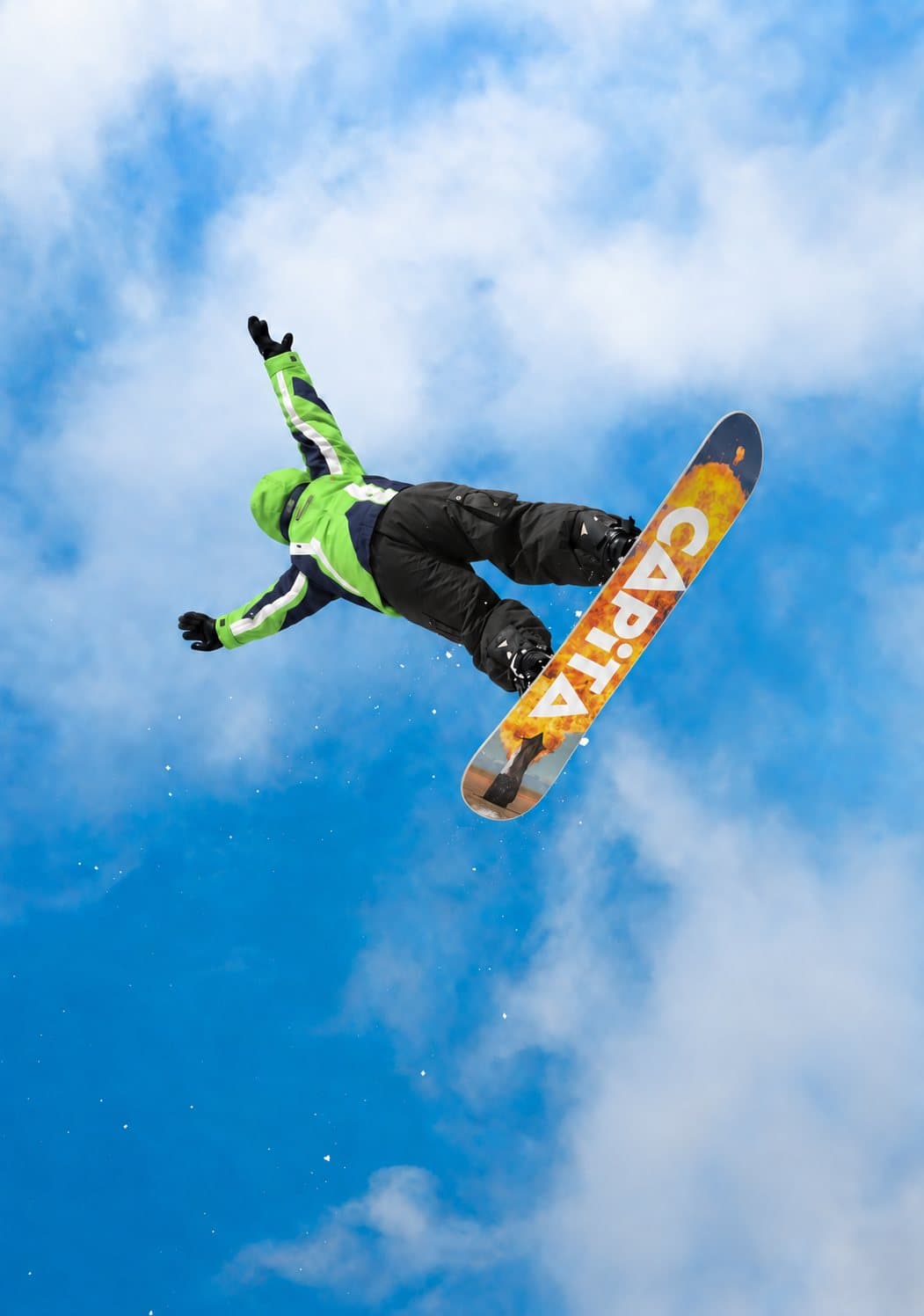 Snowboardista v zelenej bunde SKI EXPERTS počas skoku vysoko nad svahom